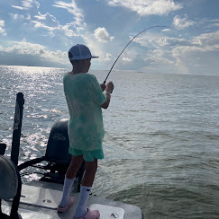 Young angler reeling in a fish on the bay