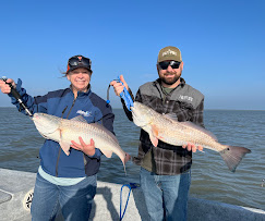 Two anglers holding redfish on a sunny day